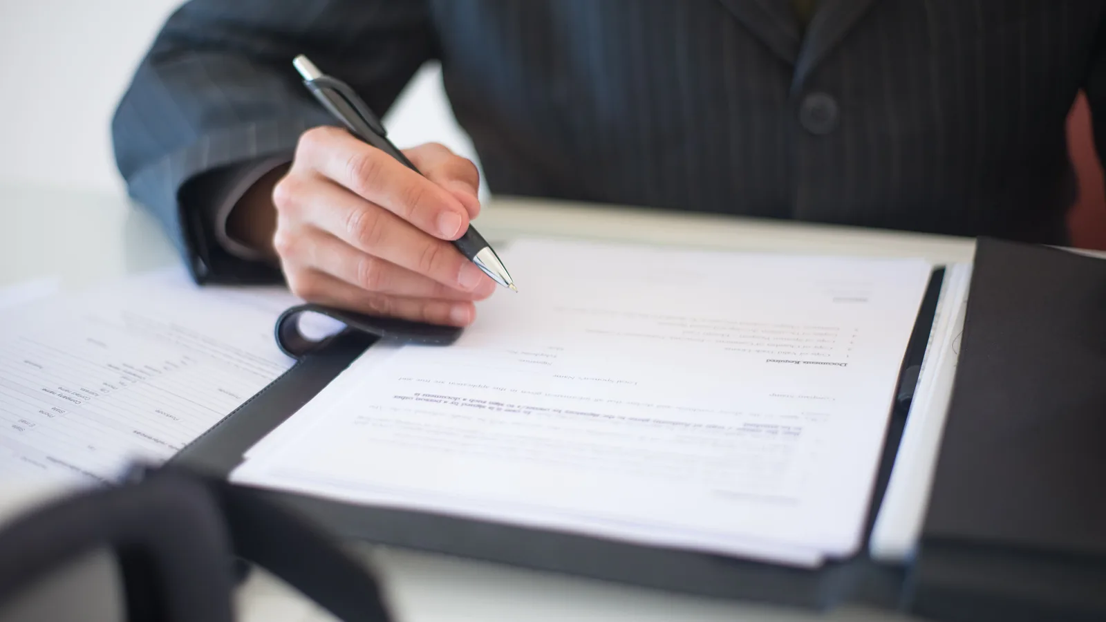 Professional reviewing contract paperwork with a pen
