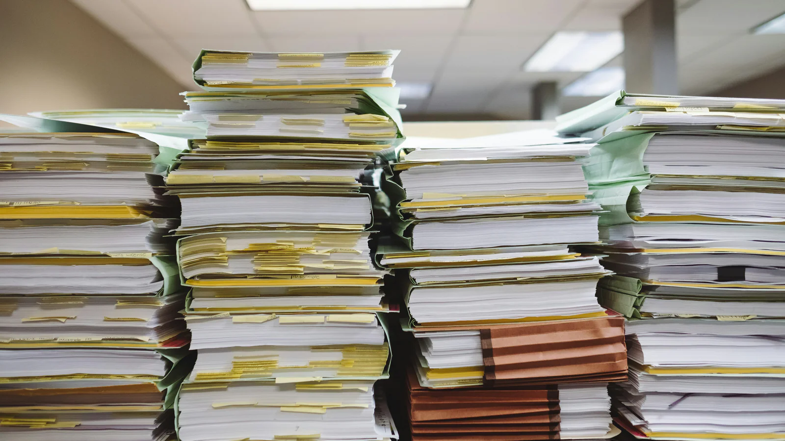 Stacks of paper files and folders in a bright office