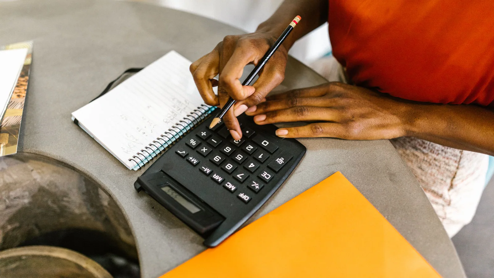 Person comparing figures with a calculator and notebook