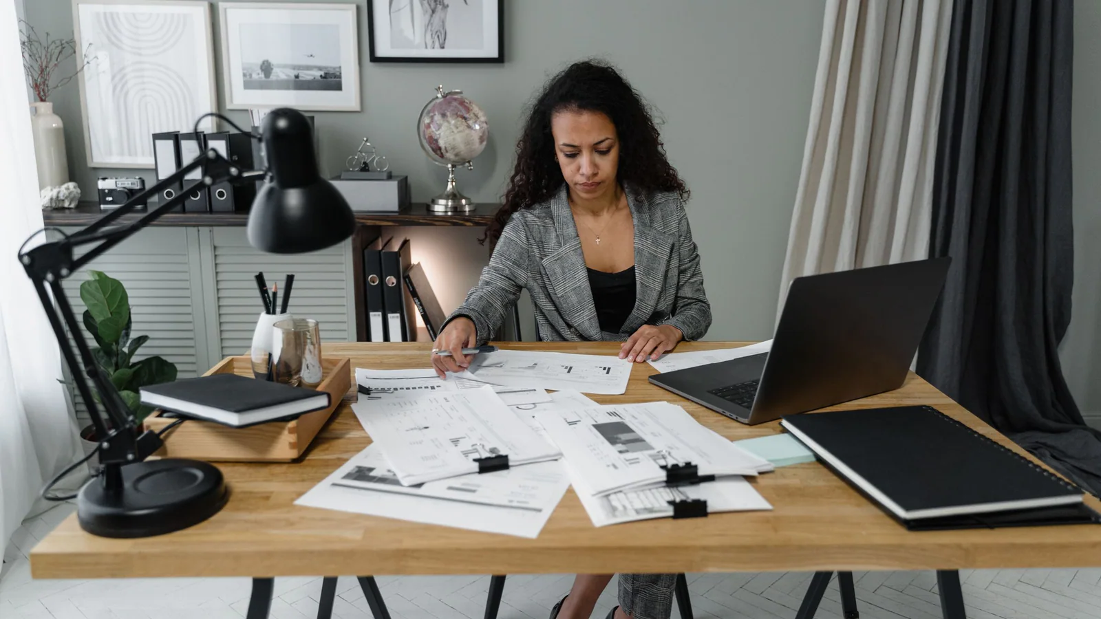 A person reviewing documents at a desk with a globe nearby
