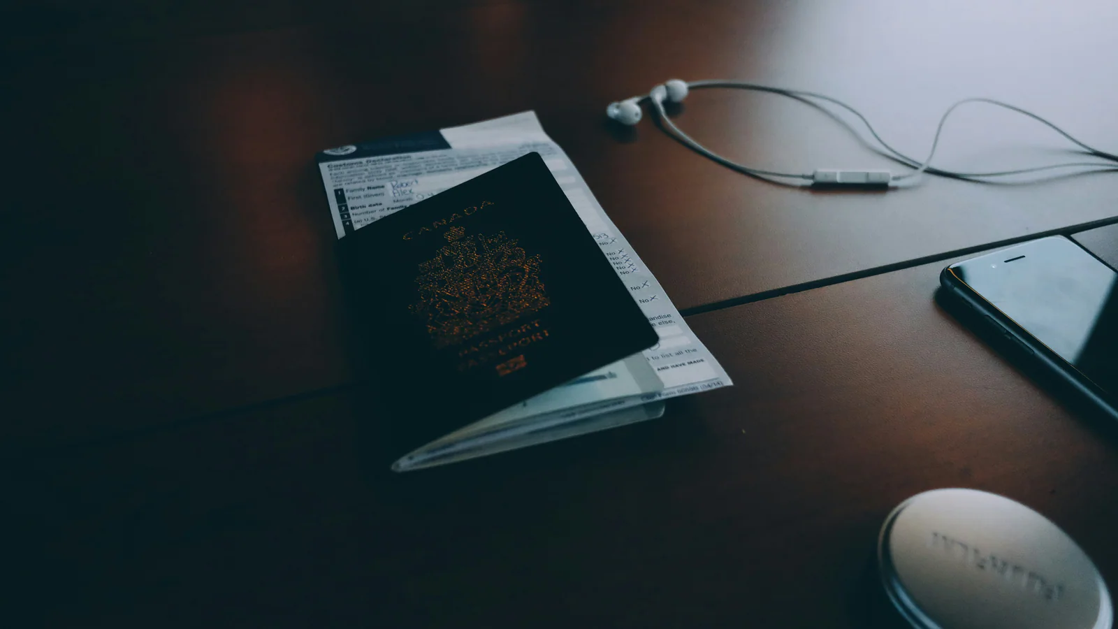 Passport beside earphones on a desk