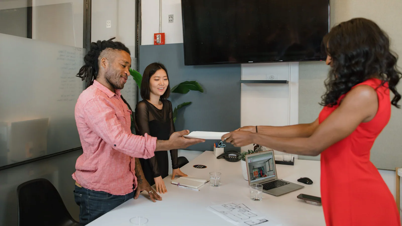 Three coworkers exchanging a document during an office meeting