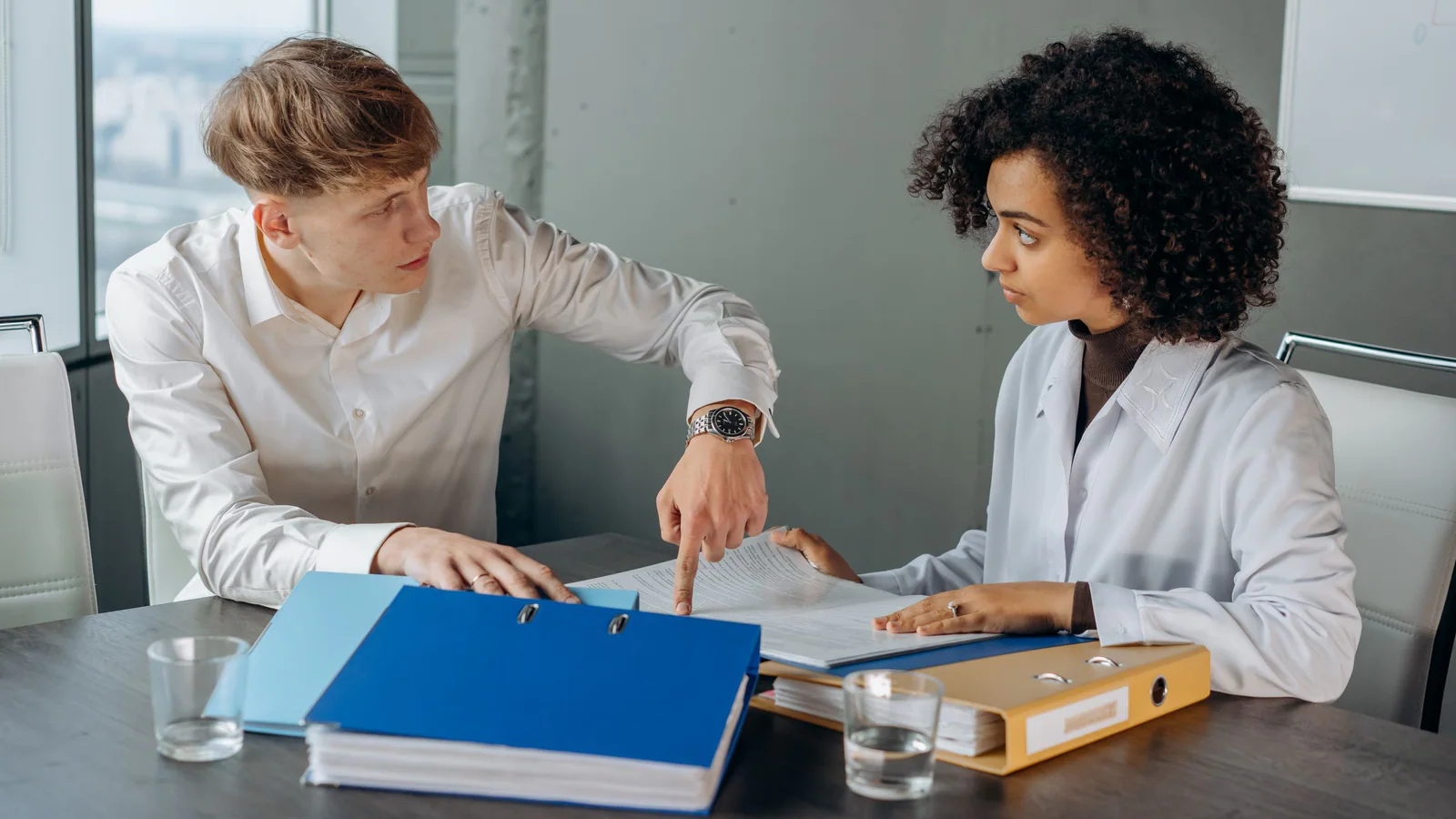 Two people reviewing papers together at an office table