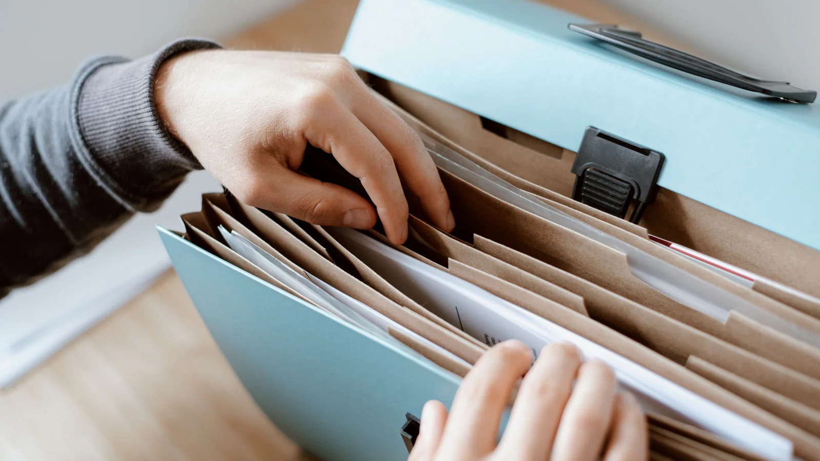 Hands sorting papers in an expanding file on a desk