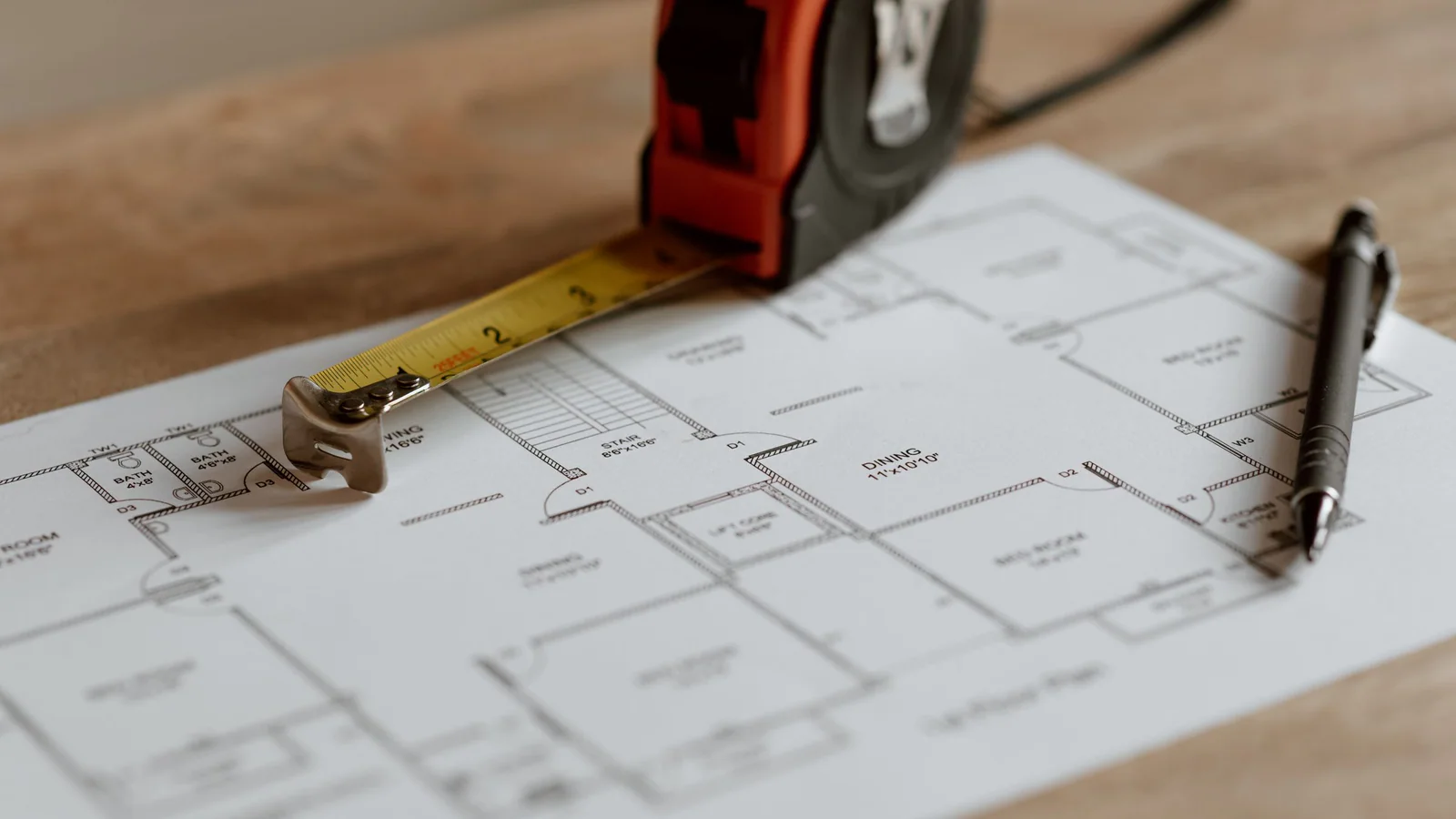 Measuring tape and pen resting on residential house plans