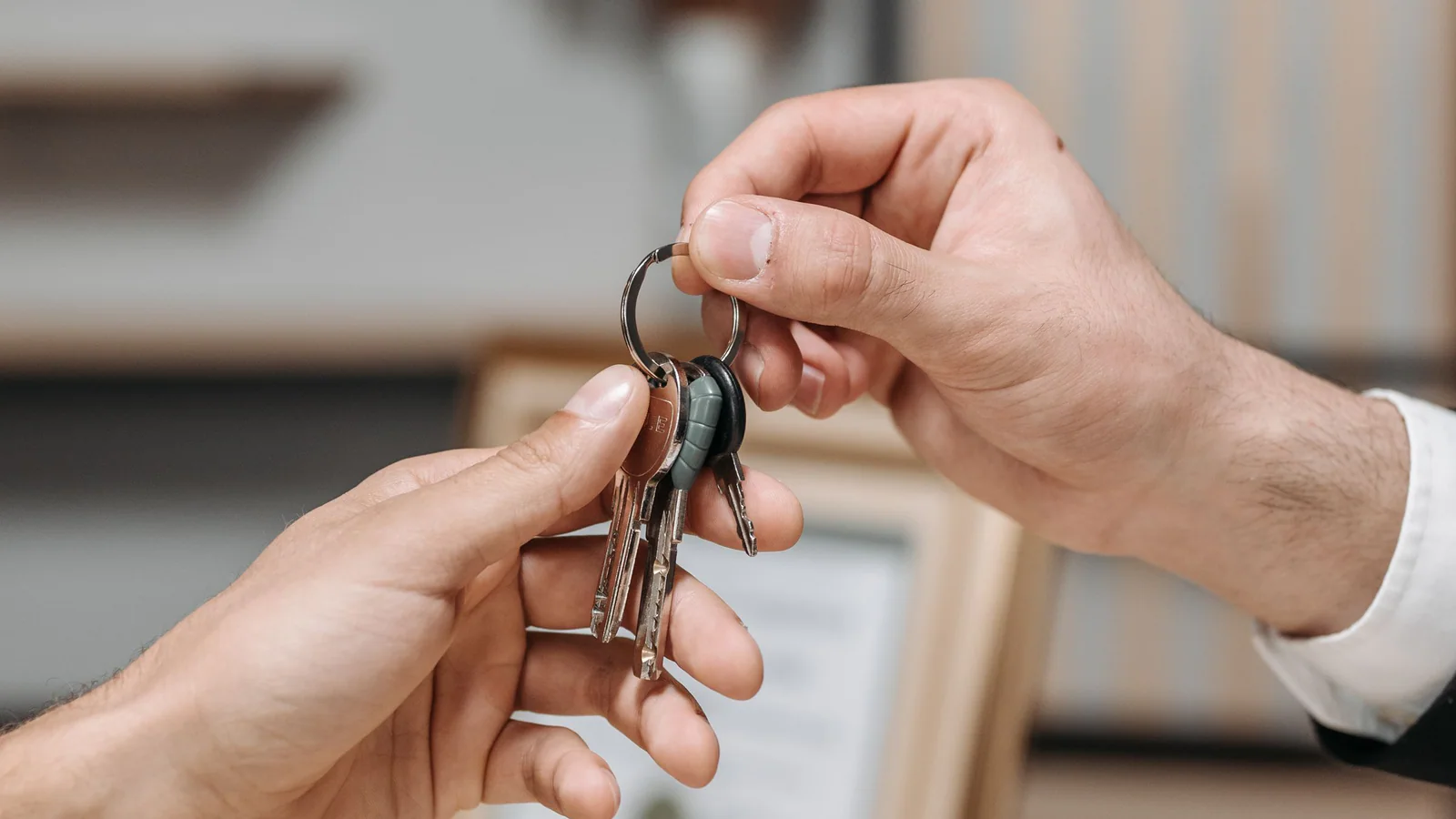 Two people exchanging a ring of property keys across a table