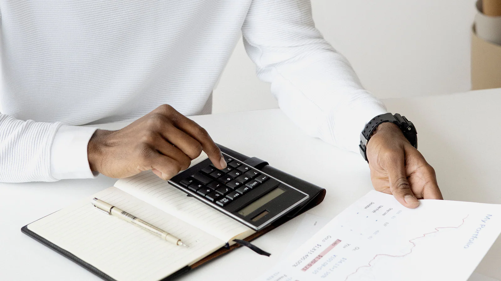 Professional reviewing charts with a calculator at an office desk