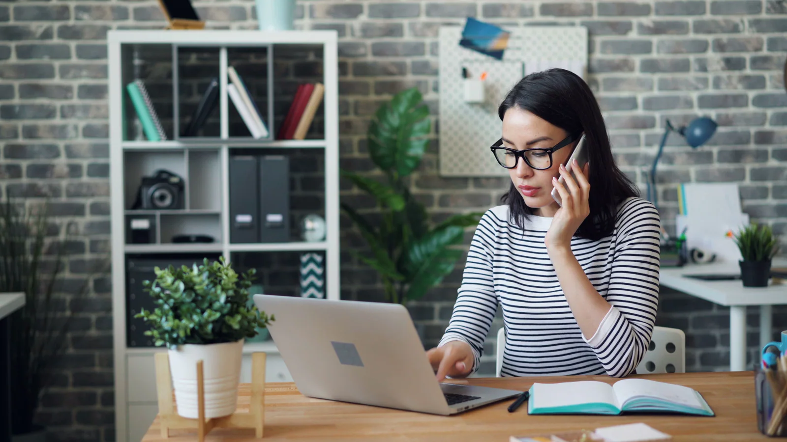 Professional using a laptop while speaking on a mobile phone