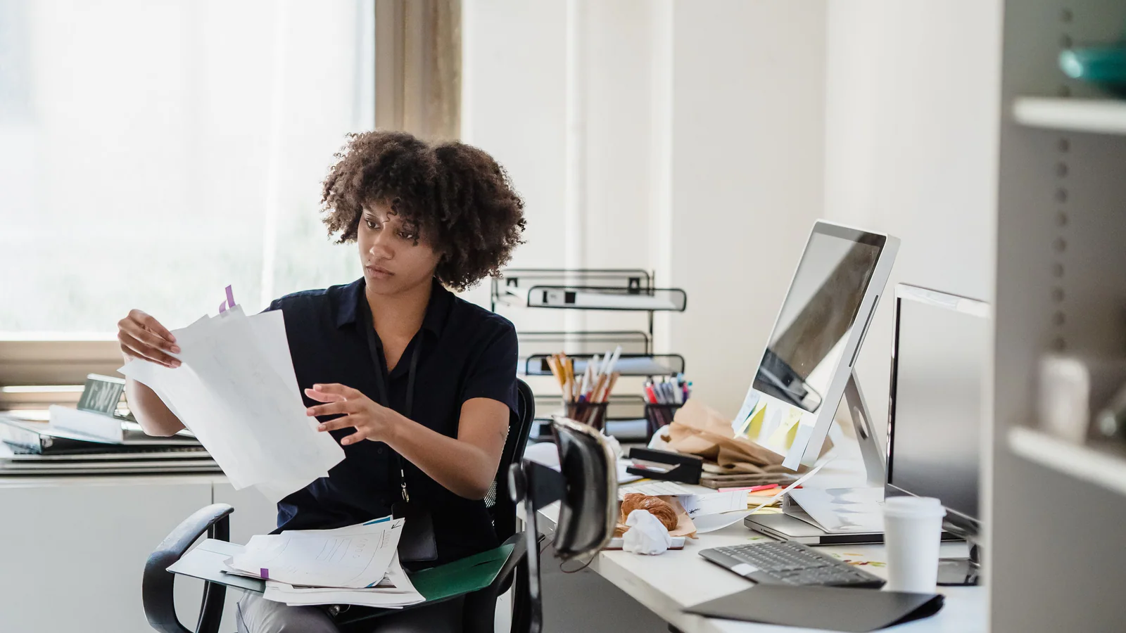 Professional reviewing documents at a busy office desk