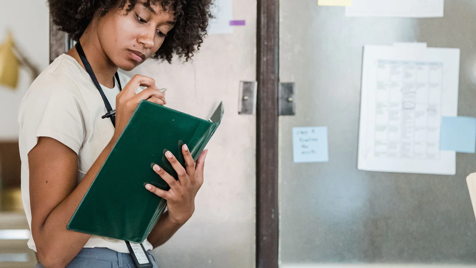 Young professional writing notes on a folder in a modern office