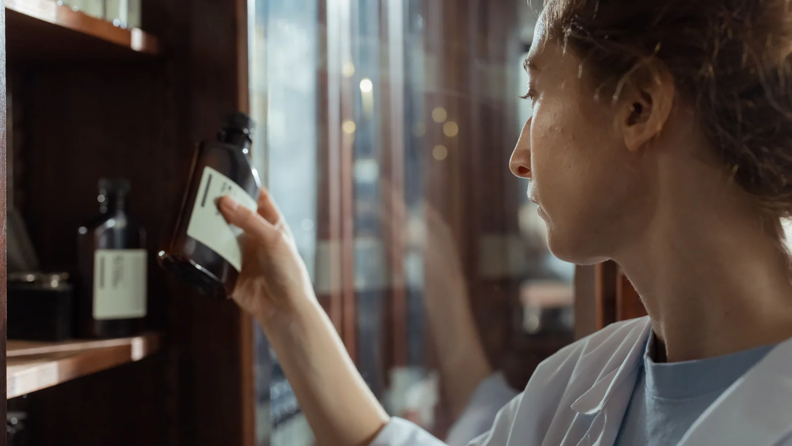 Person in a lab coat examining a generic medicine bottle label