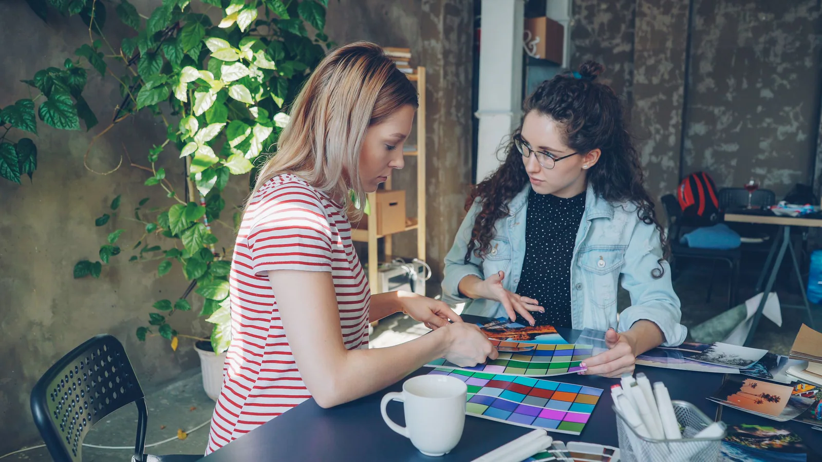 Two people reviewing colour swatches and printed images at a desk