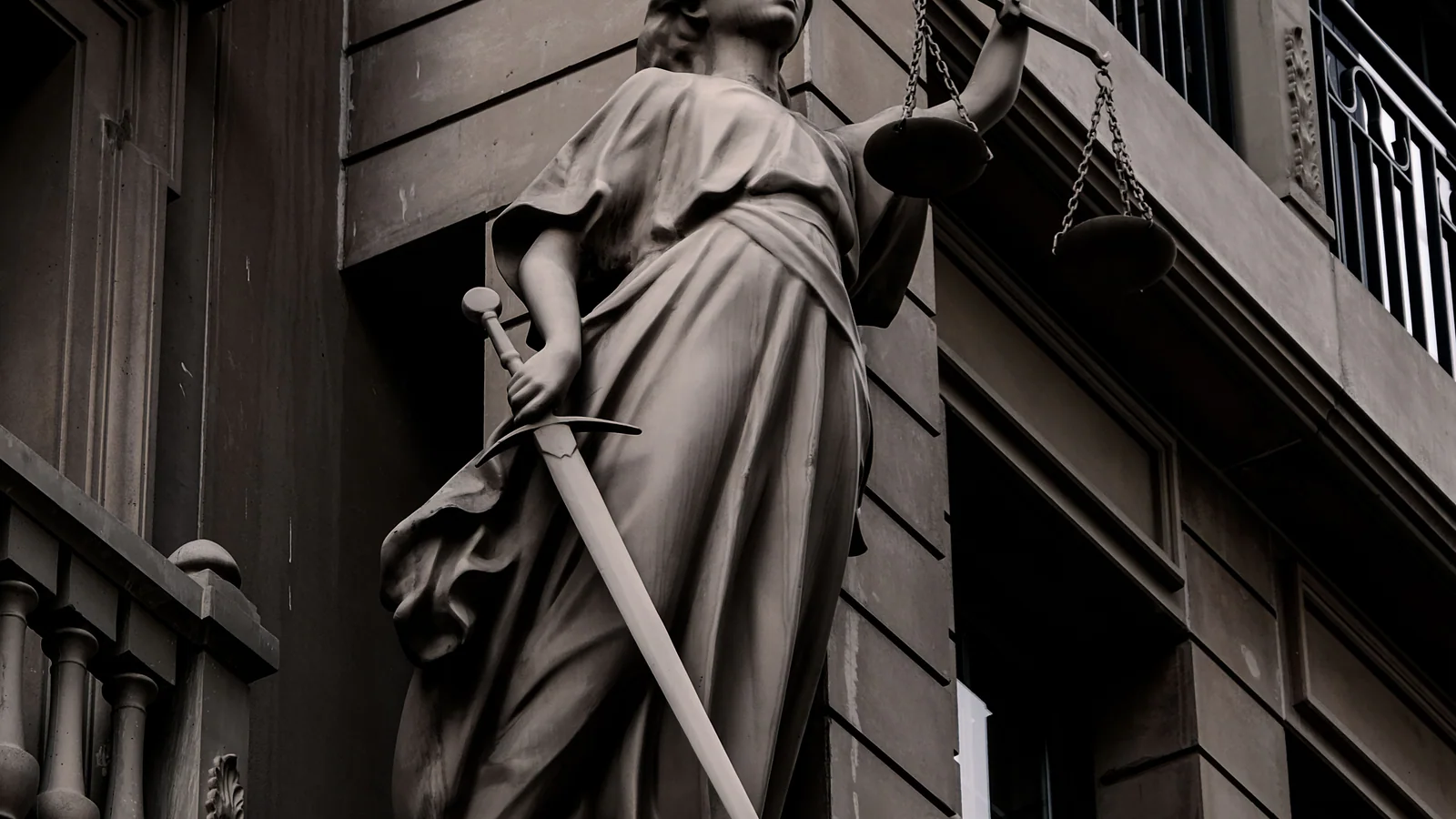 Justice sculpture with scales on an urban building facade