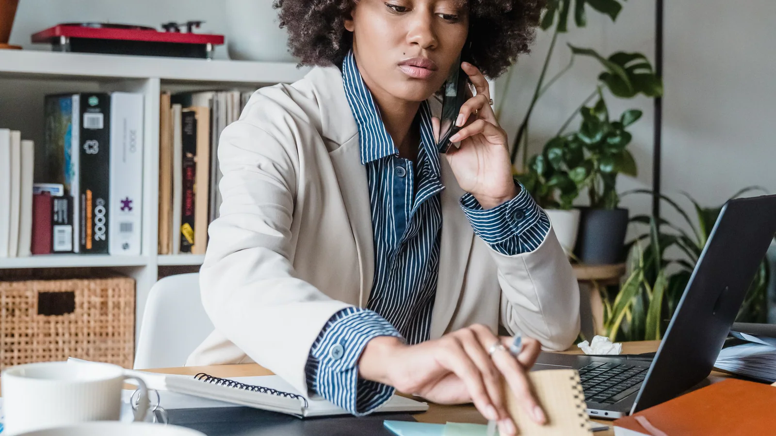 Person reviewing documents while making a phone call beside a laptop