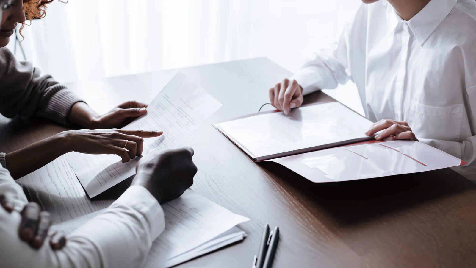 Three people reviewing documents at a consultation table