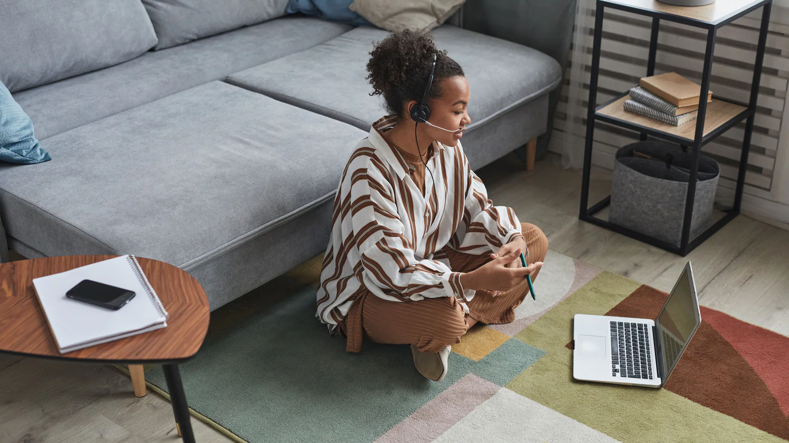 Professional taking part in a remote call with a laptop and notebook at home