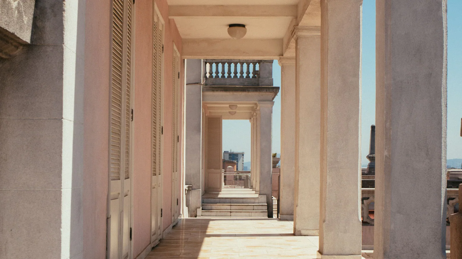 Sunlit empty corridor with pale columns and doorways