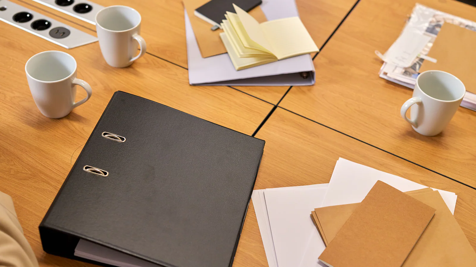 Ring binder, papers and envelopes arranged on a wooden office table
