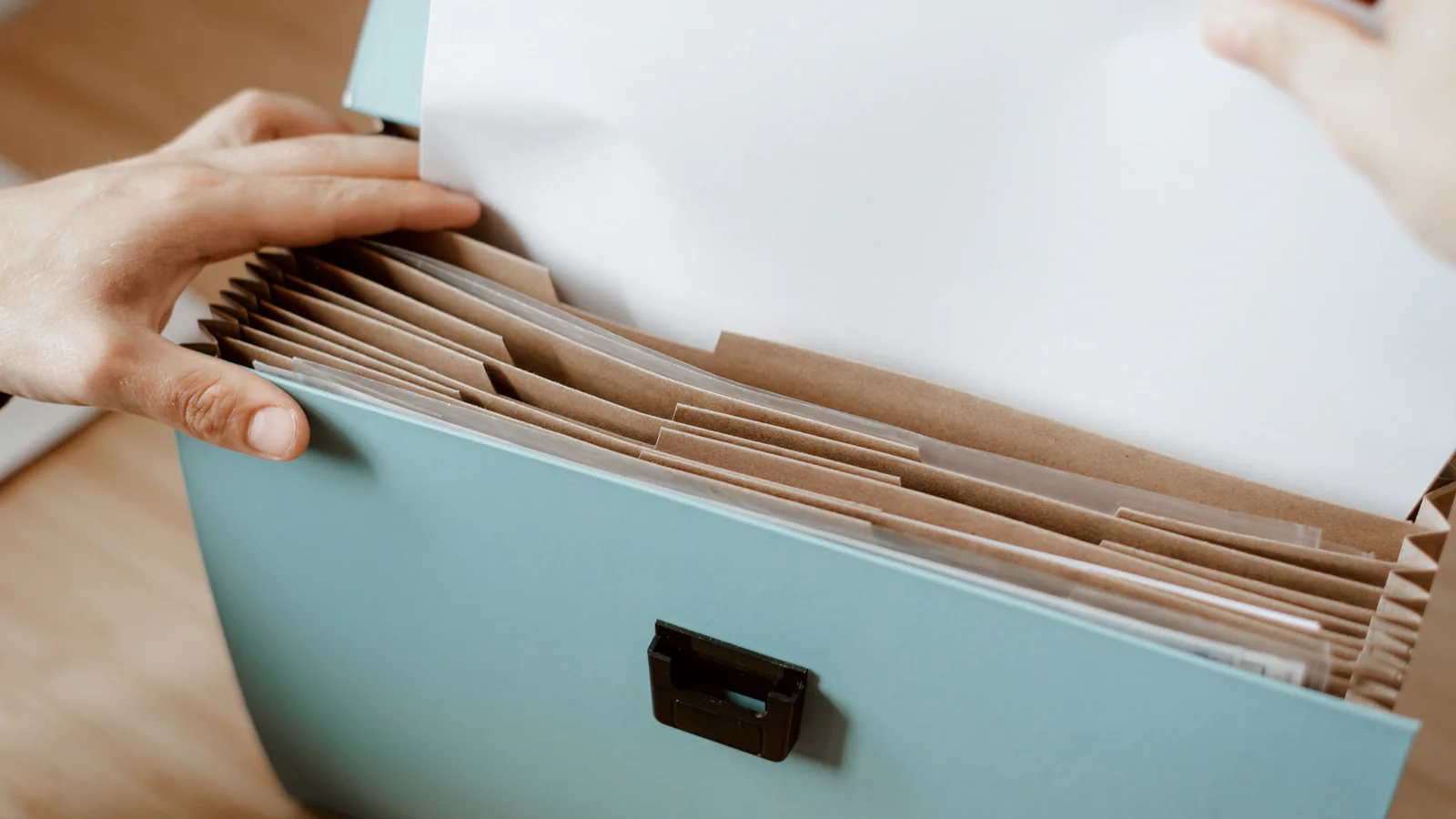 Hands filing a blank sheet in an office document organiser