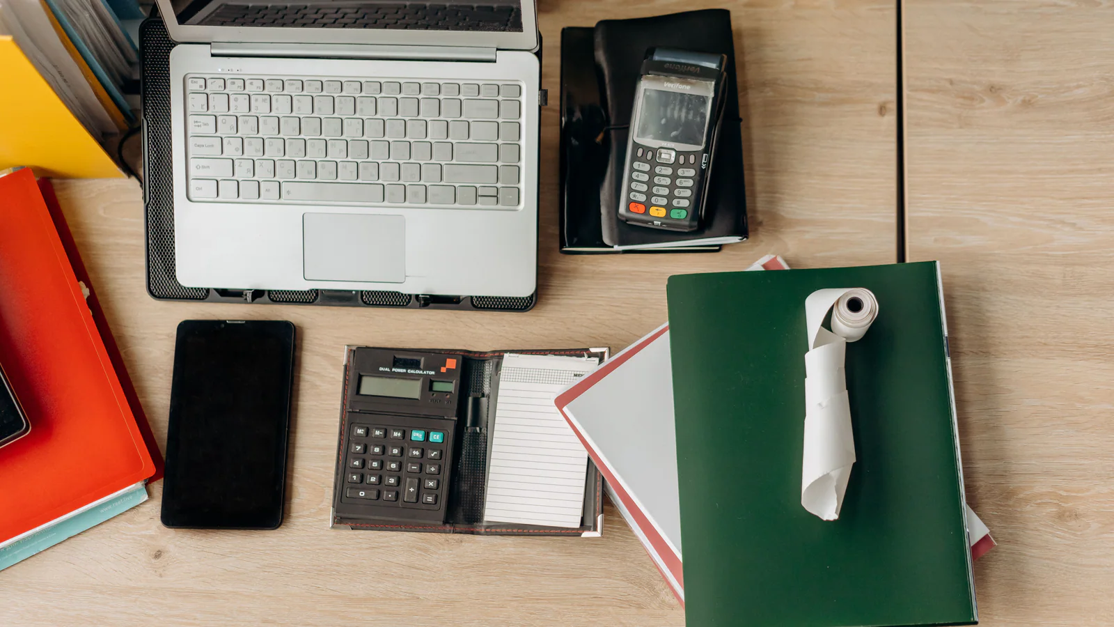 Calculator, laptop and notebooks arranged on an office desk