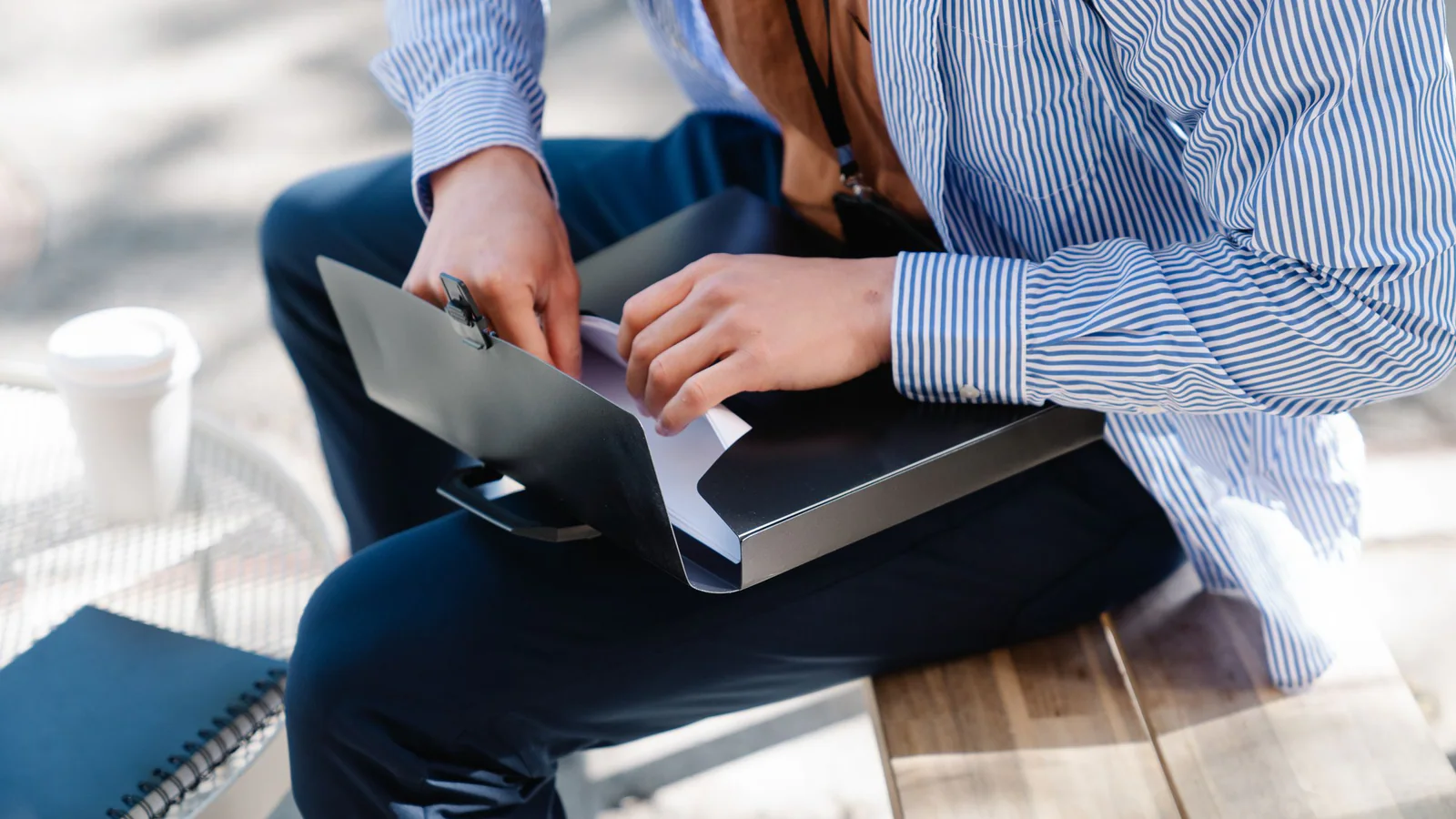 Person reviewing papers in a folder on a bench