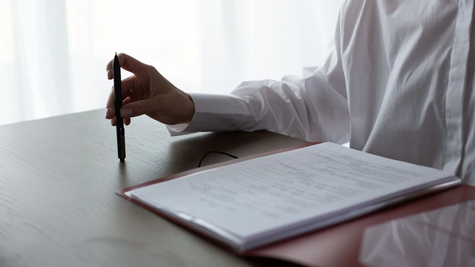 Person reviewing documents with a pen at a table