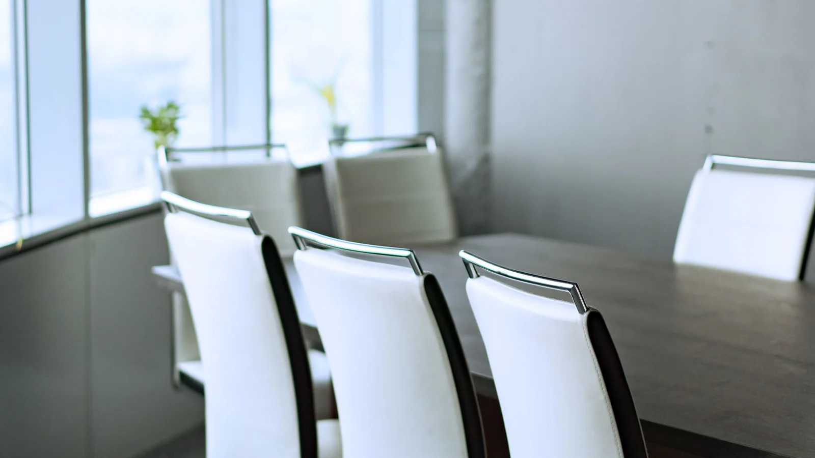Empty meeting room with white chairs around a conference table