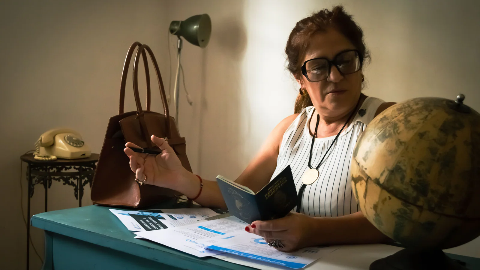 Person reviewing a passport beside a globe at a desk