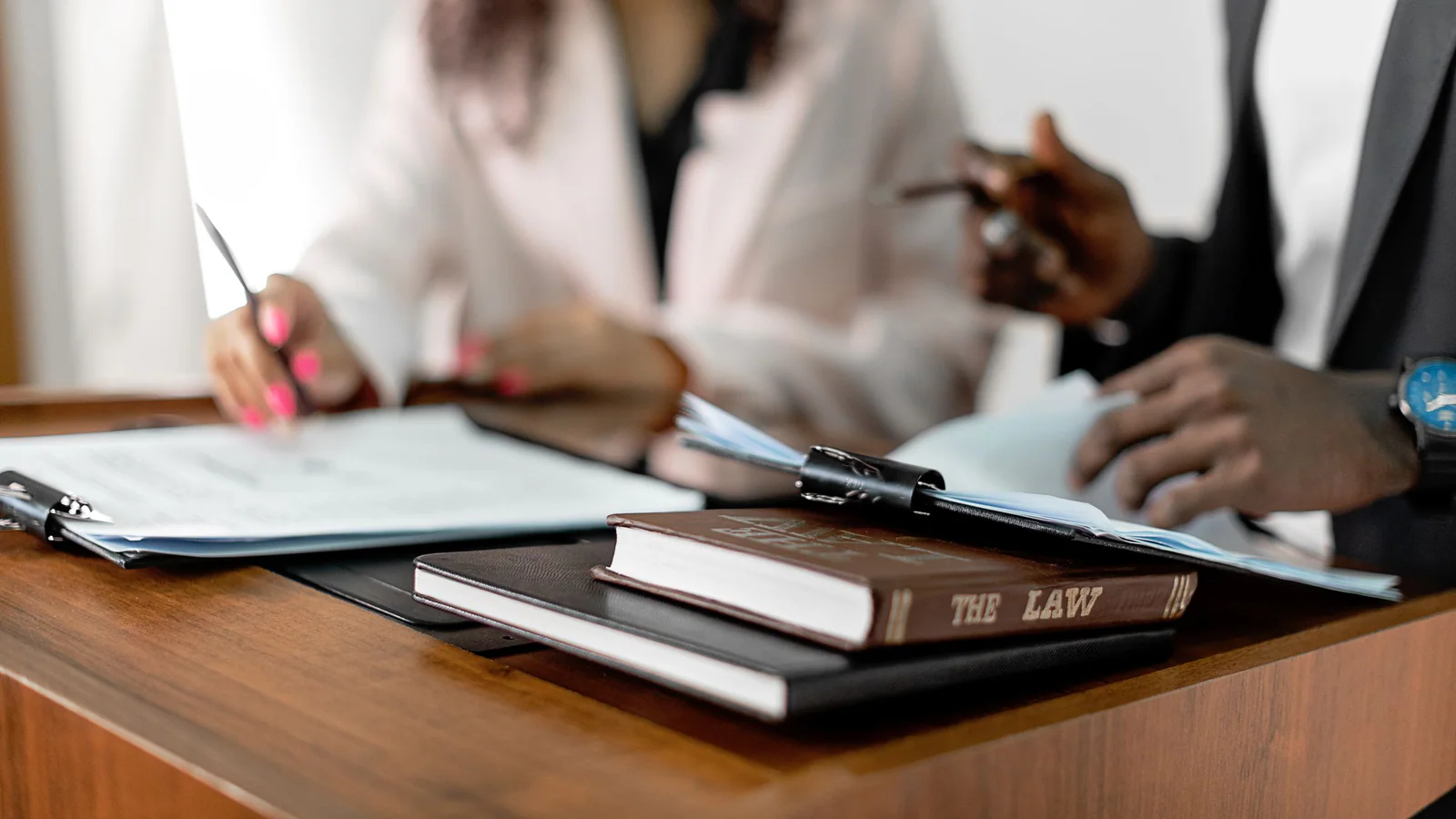 Two professionals reviewing documents at a desk beside law books