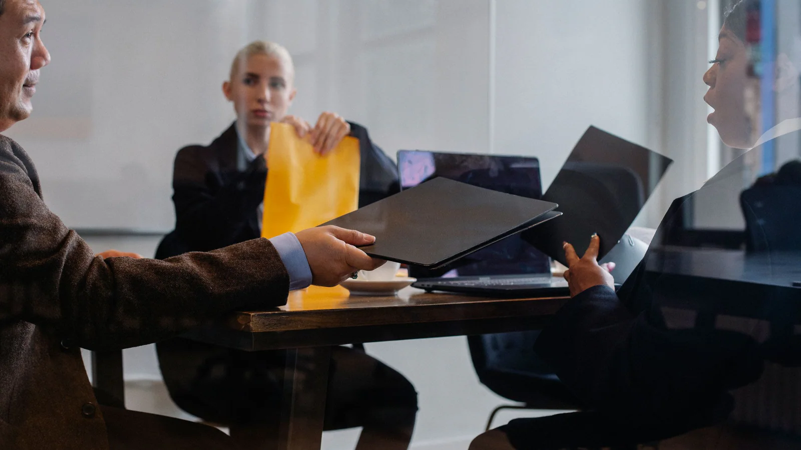 Three professionals coordinating around closed folders in an office