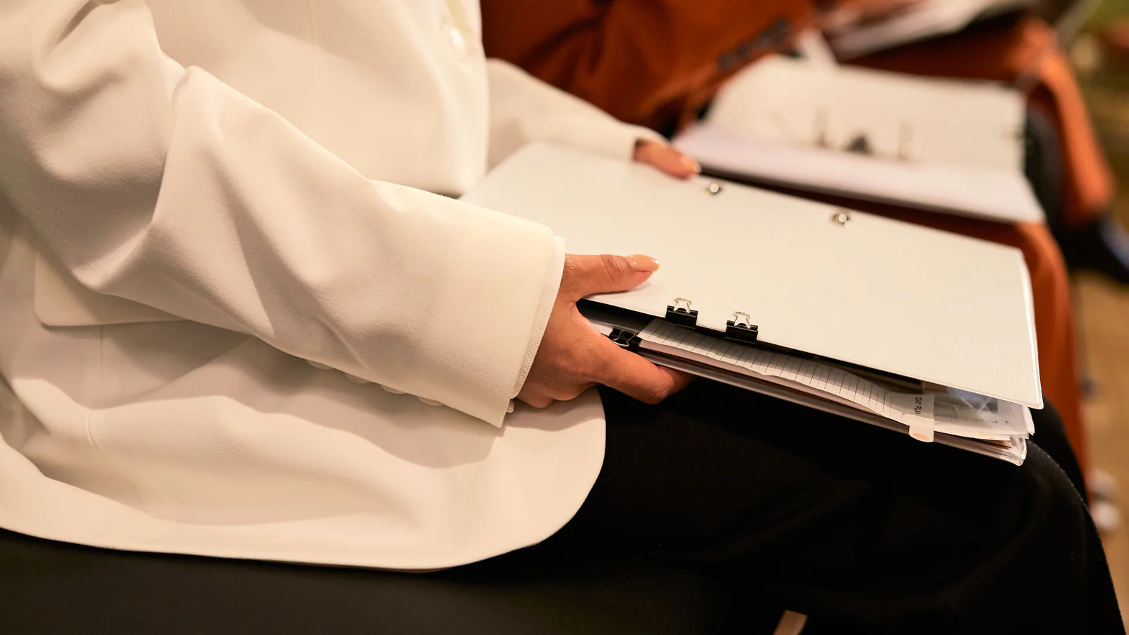 A person holding several closed folders and documents during an office meeting