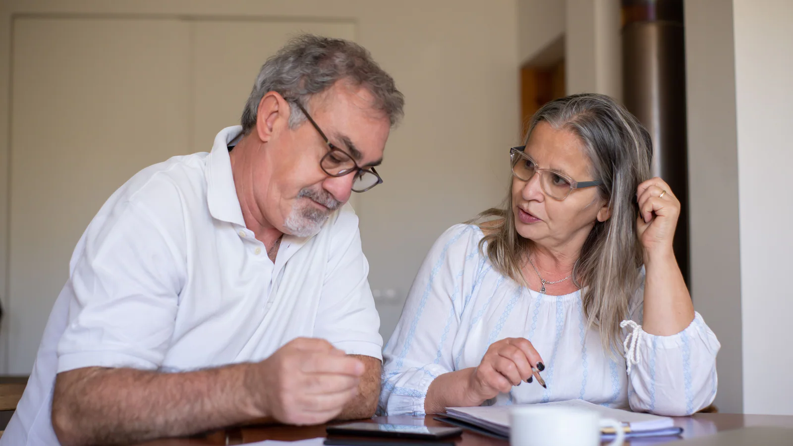 Two older adults reviewing documents together at a table