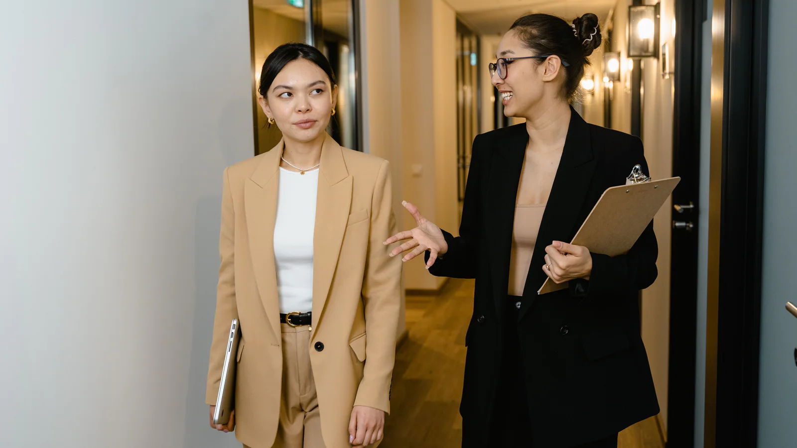 Two professionals discussing documents while walking through an office hallway