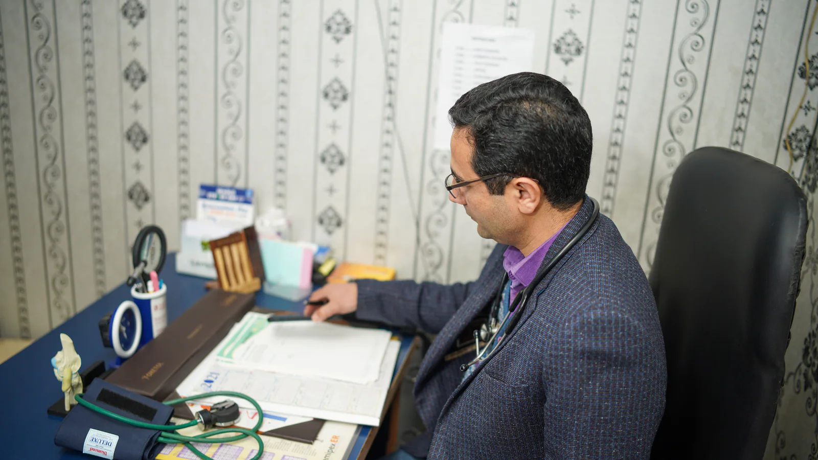 Doctor reviewing medical records at a clinic desk