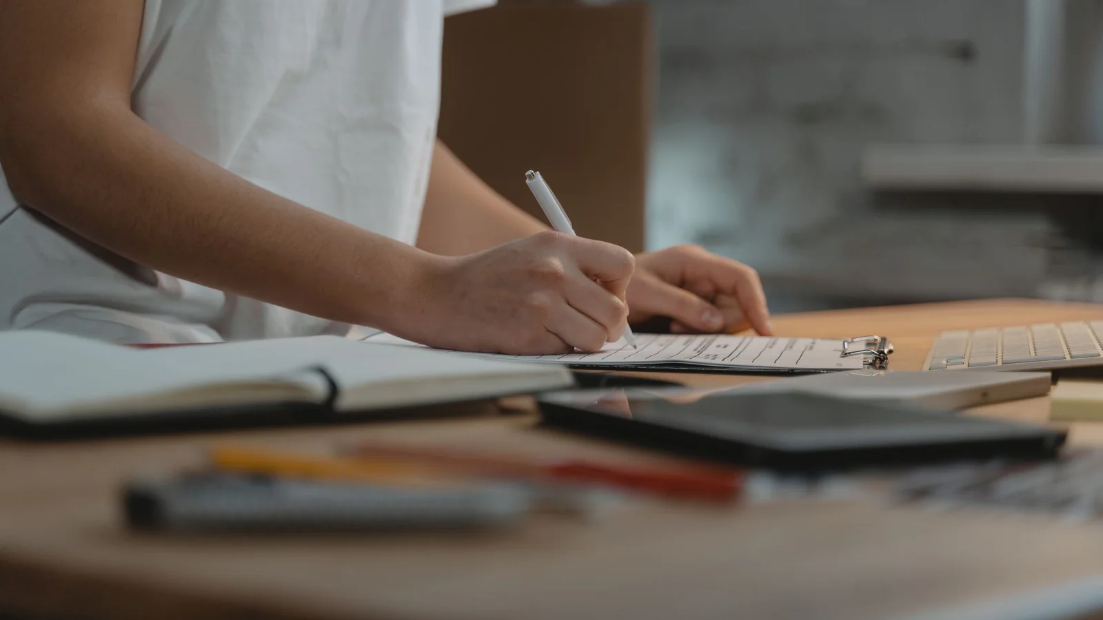 Person completing a form on a clipboard at a desk