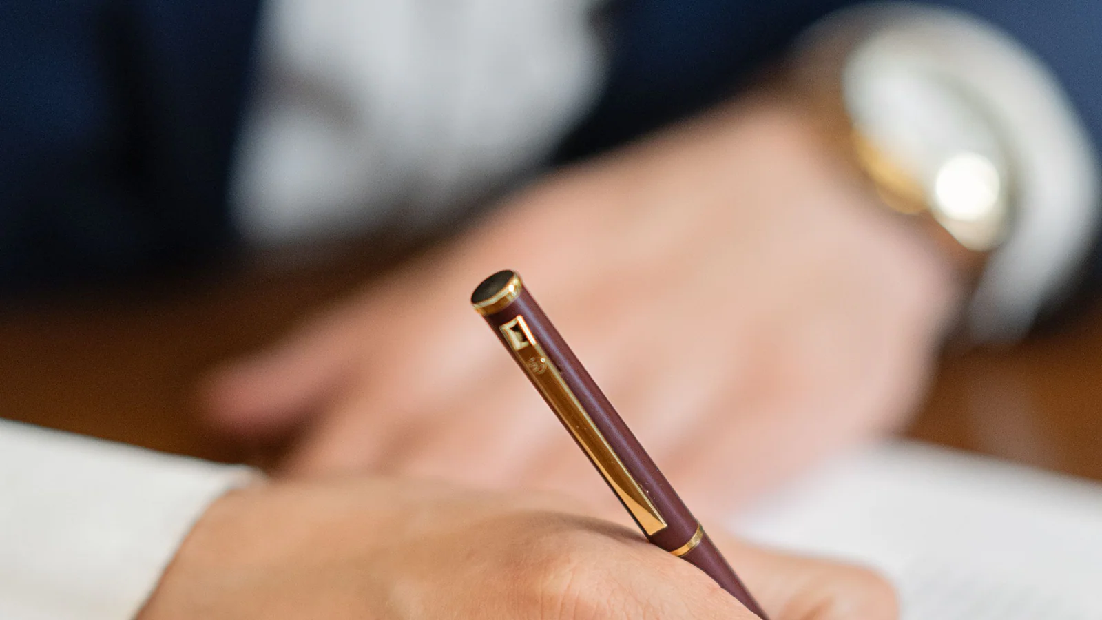 Close-up of a hand using a fountain pen on an indistinct document