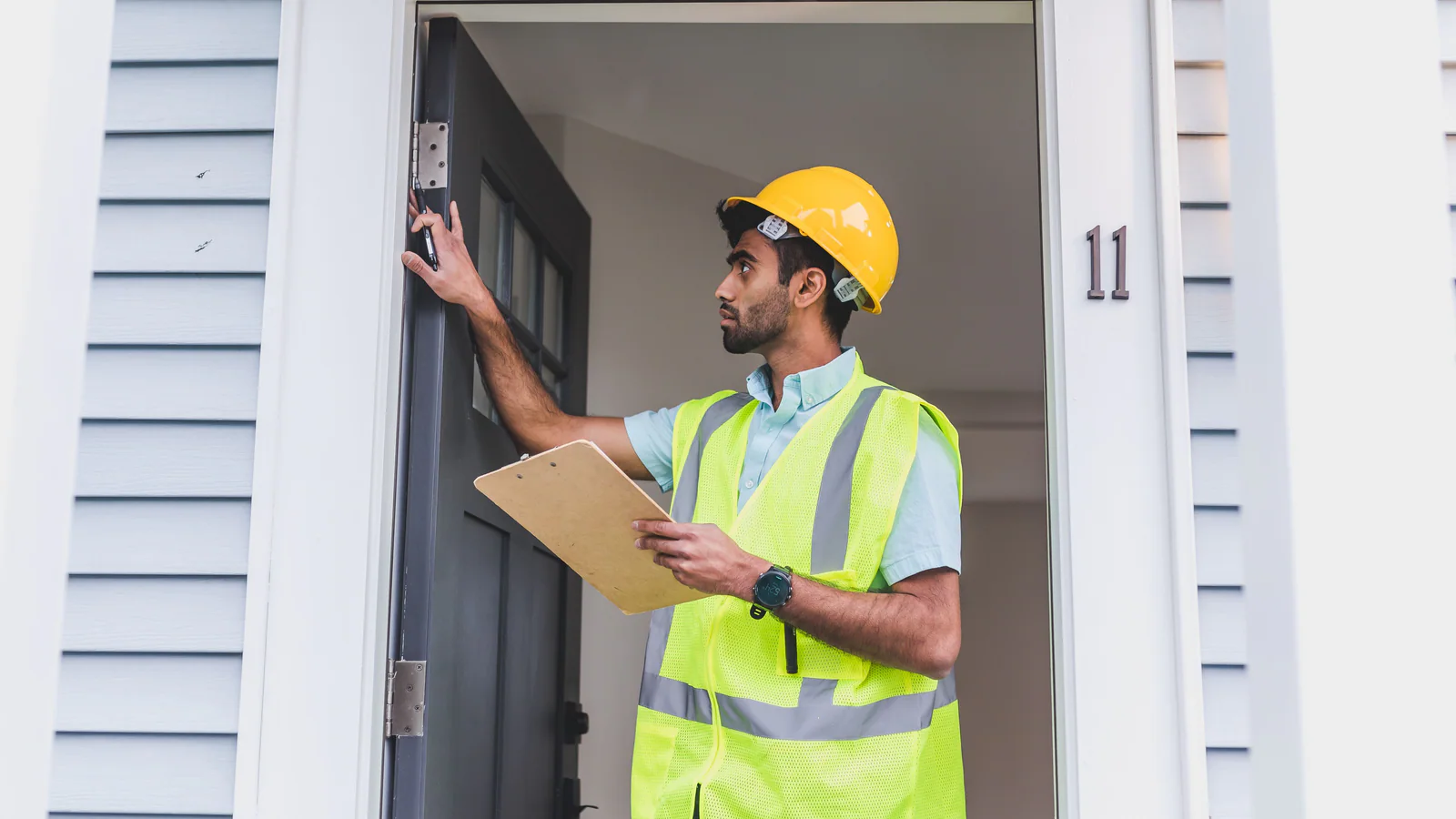 Home inspector checking a door frame while holding a clipboard