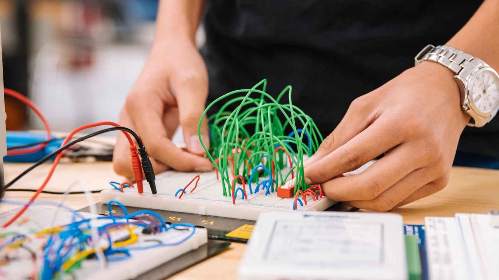 Hands connecting wires on an electronics prototype breadboard