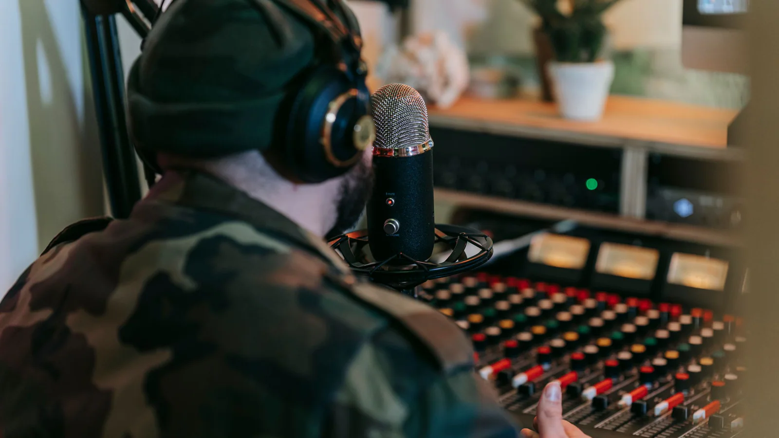 Musician in headphones recording at a studio microphone and mixing console