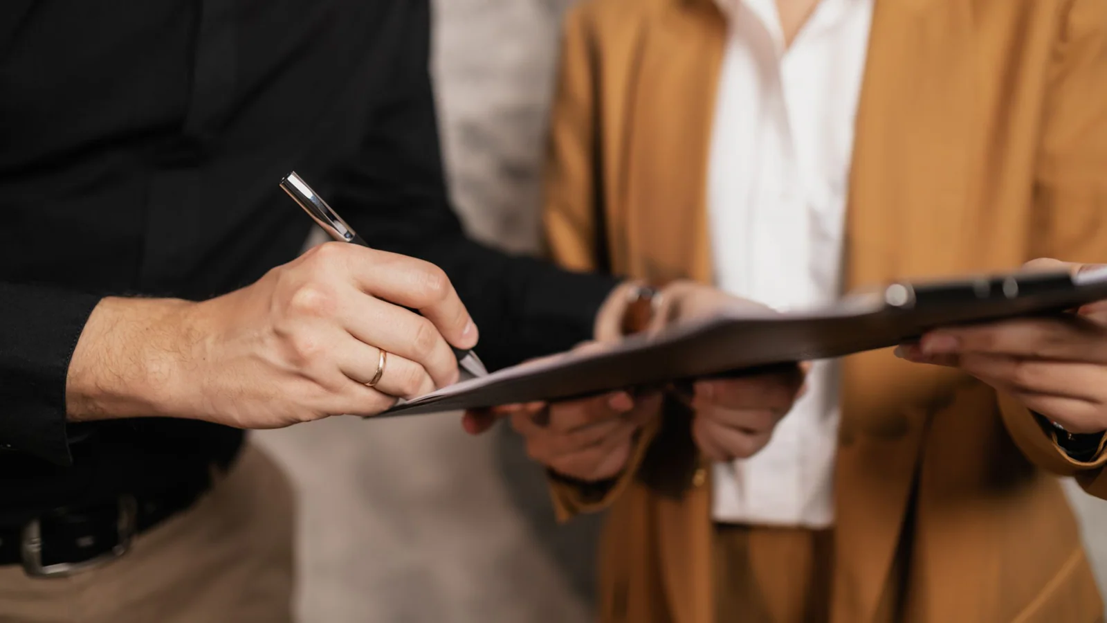 Two people reviewing and signing a document on a clipboard