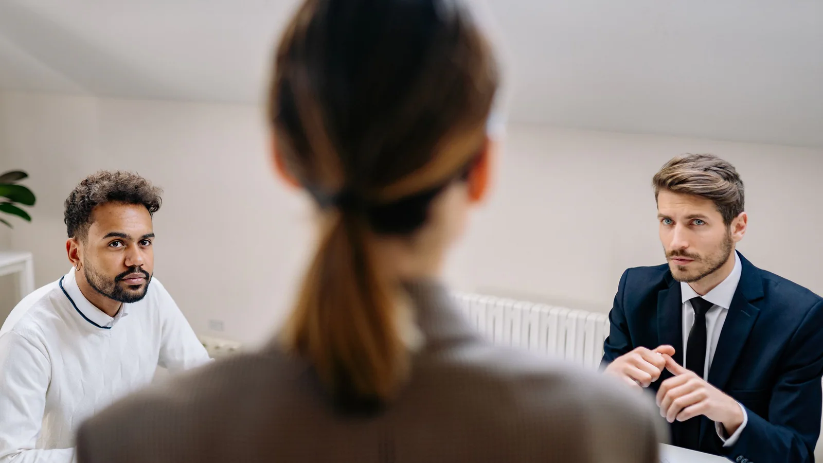Three people having a serious discussion across an office table