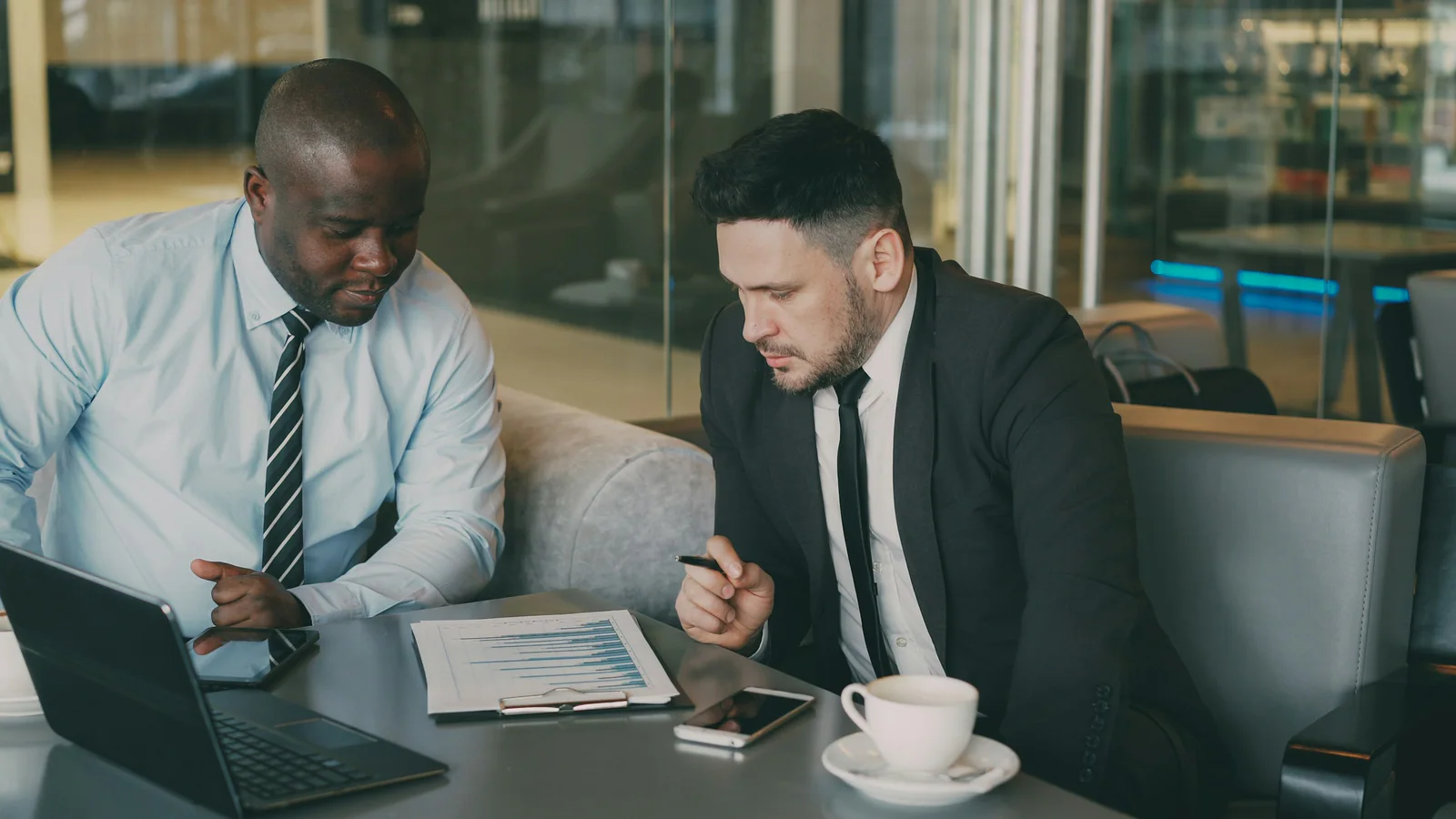 Two people reviewing papers beside a laptop