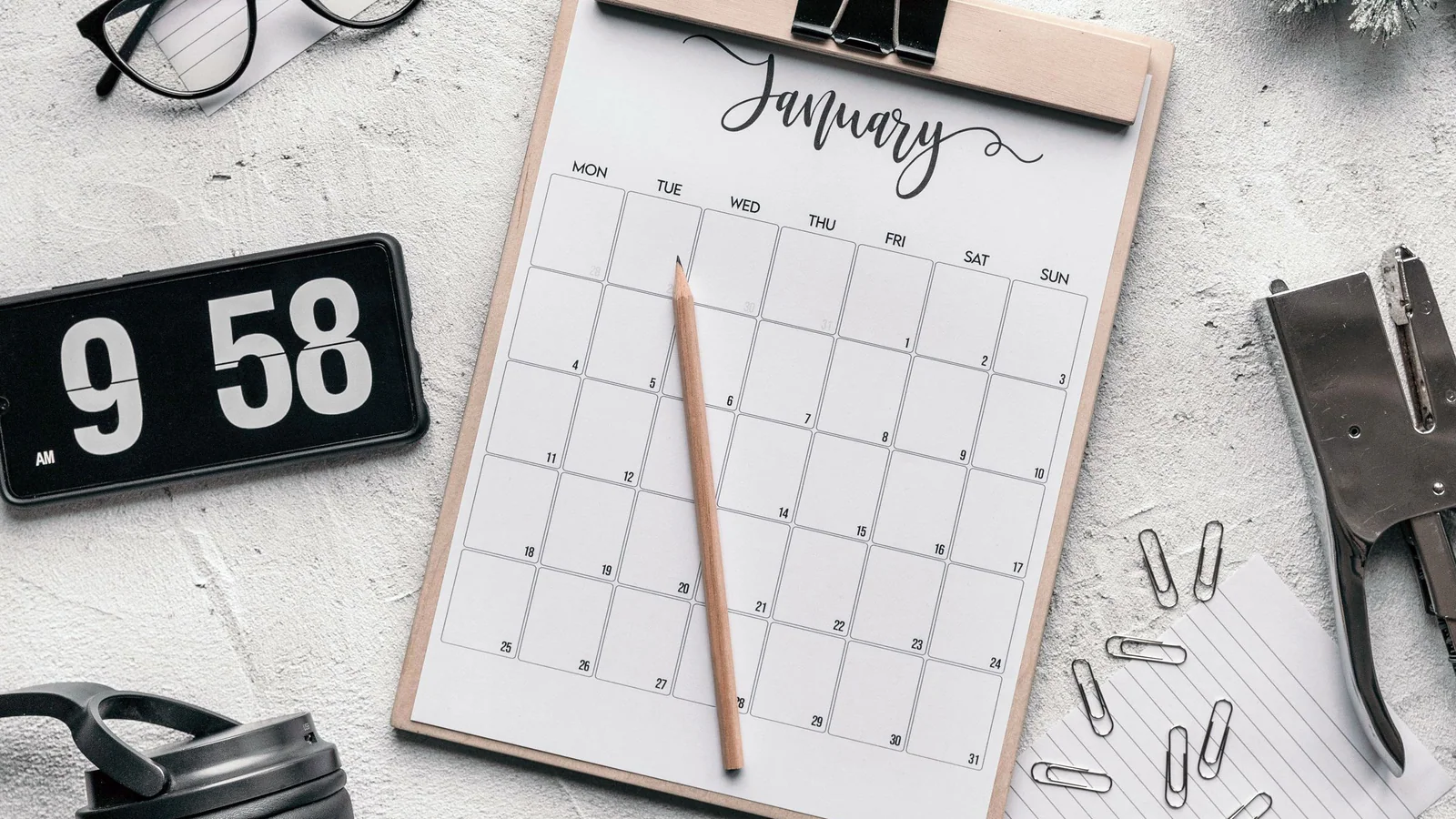 Calendar, clock and stationery arranged on a desk