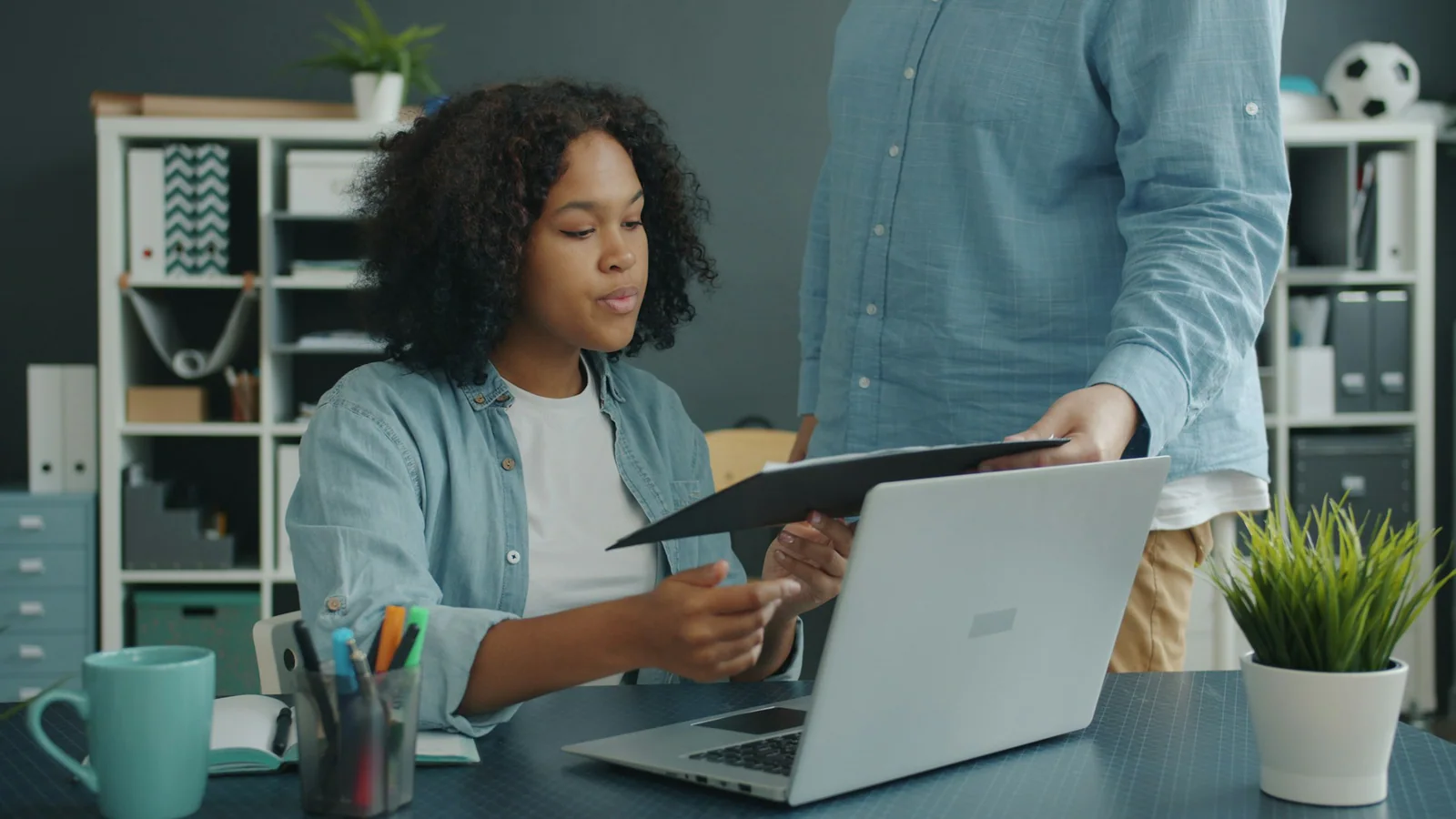 Two colleagues reviewing documents beside a laptop in an office