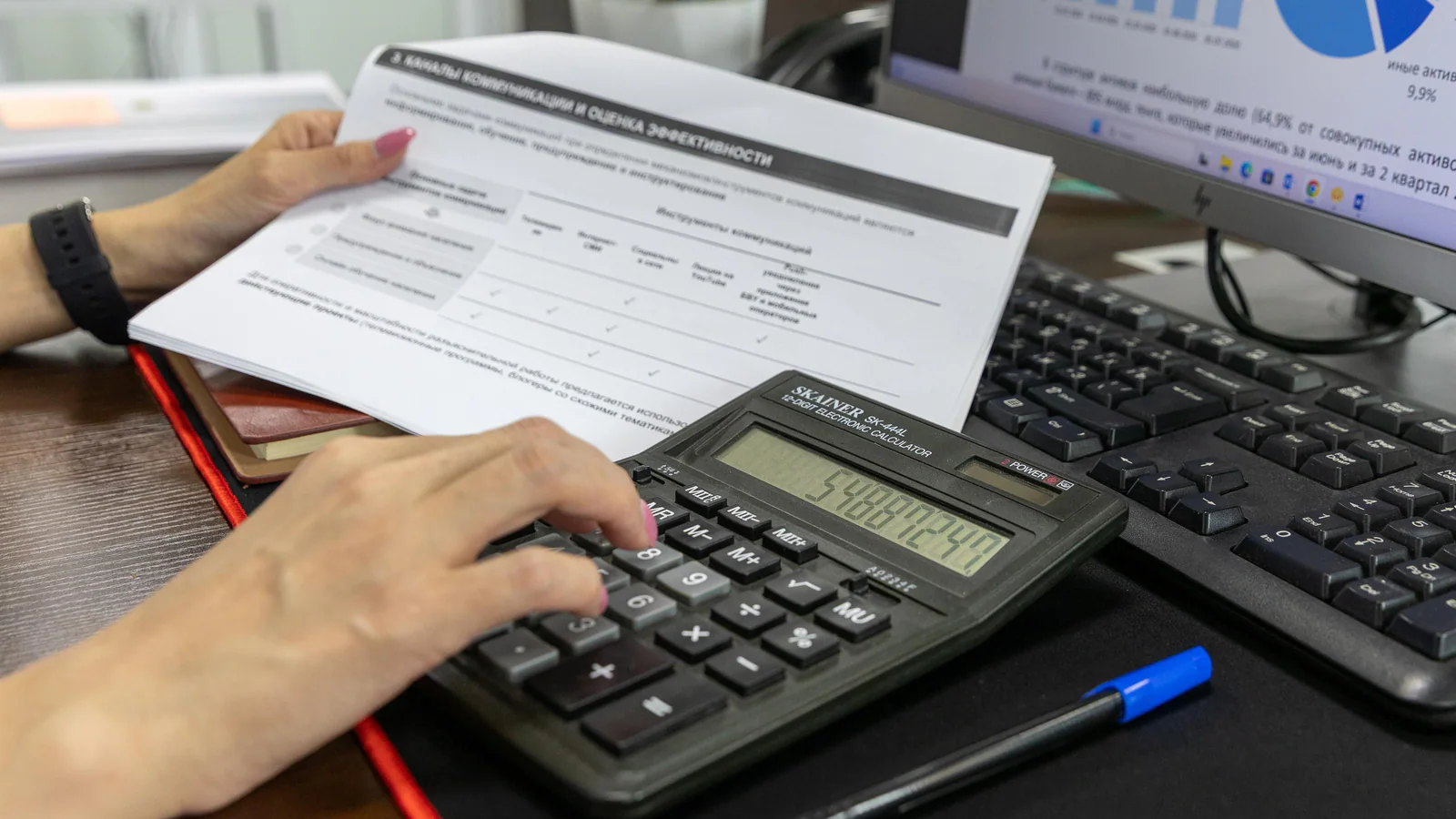 Hand checking figures and documents at an office desk