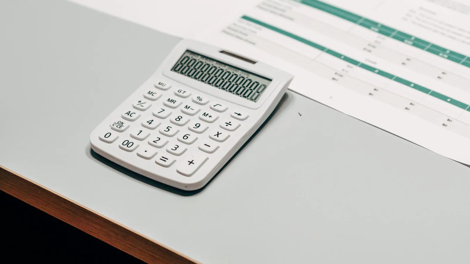 Calculator beside a blurred financial worksheet