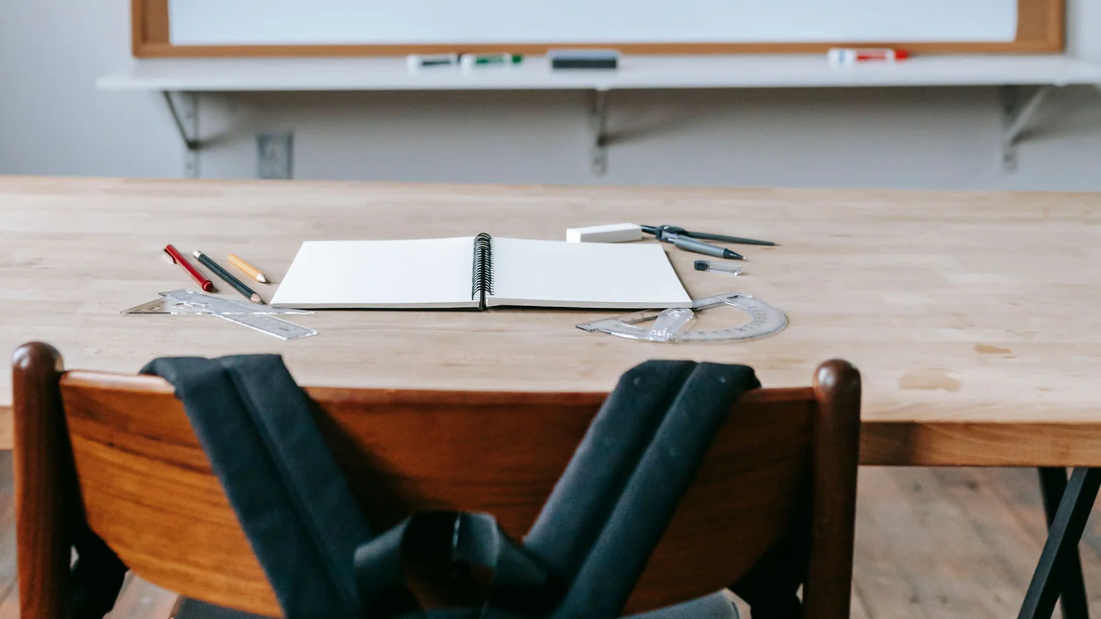Blank notebook on a classroom desk facing an empty chair