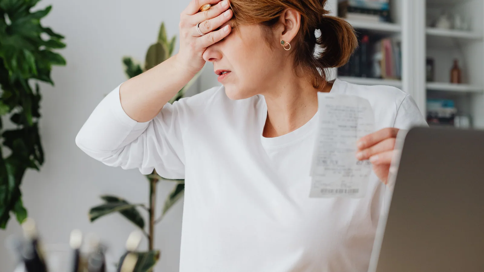 Woman reviewing a receipt beside a laptop