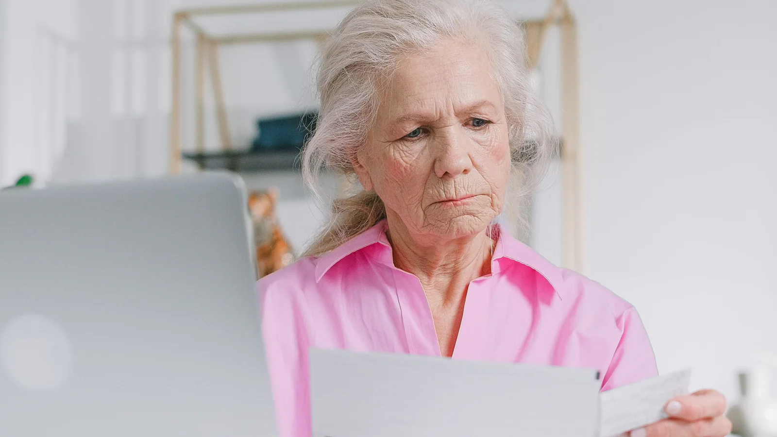 Older woman reviewing papers beside a laptop