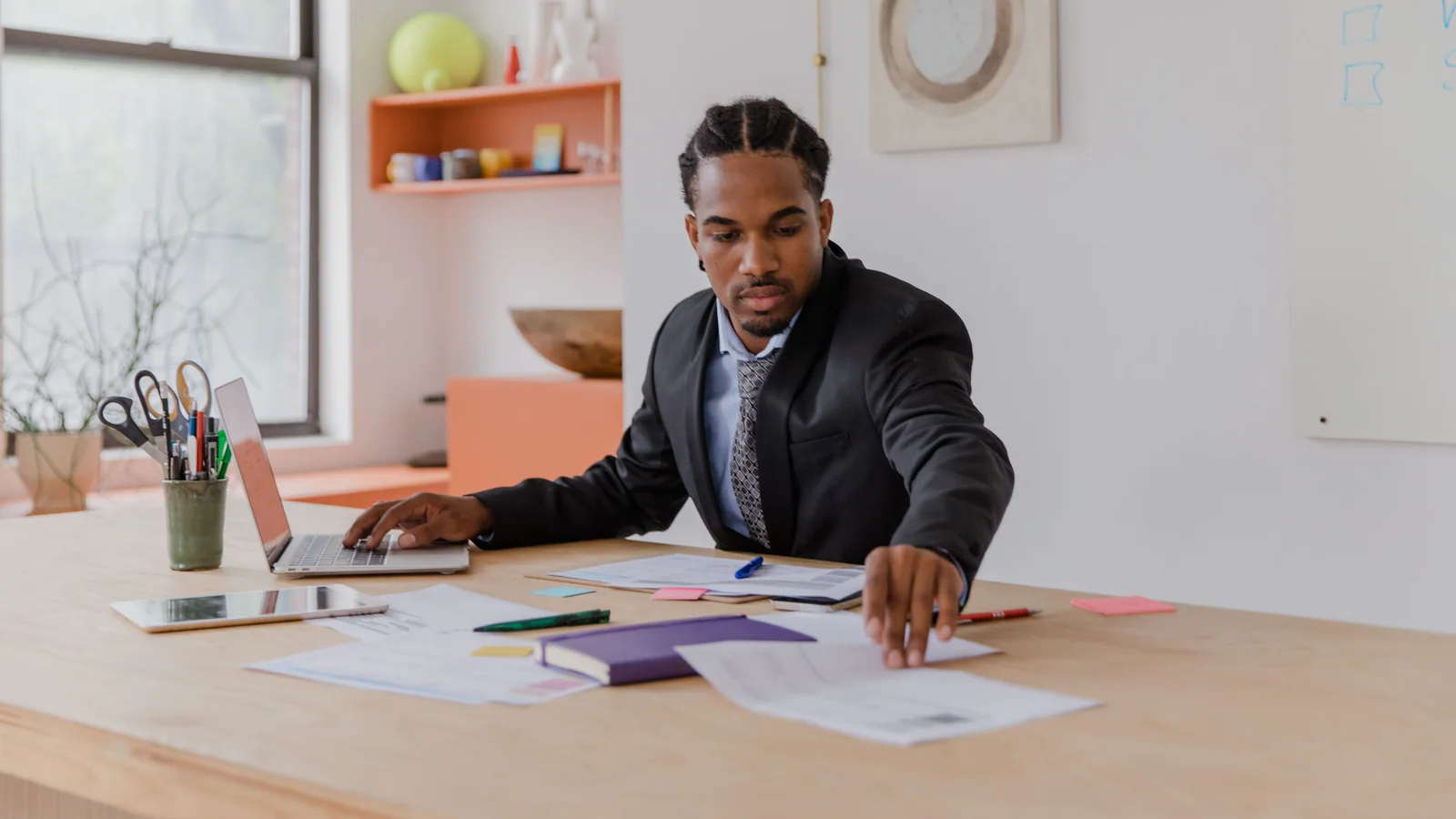 Professional reviewing documents beside a laptop at an office desk